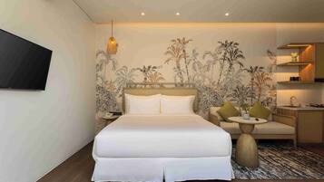 Una habitación de hotel con cama, televisión, una mesita, sofá y una zona de cocina.