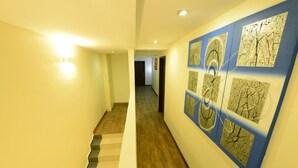 A hallway with wooden flooring, a staircase, and wall art.