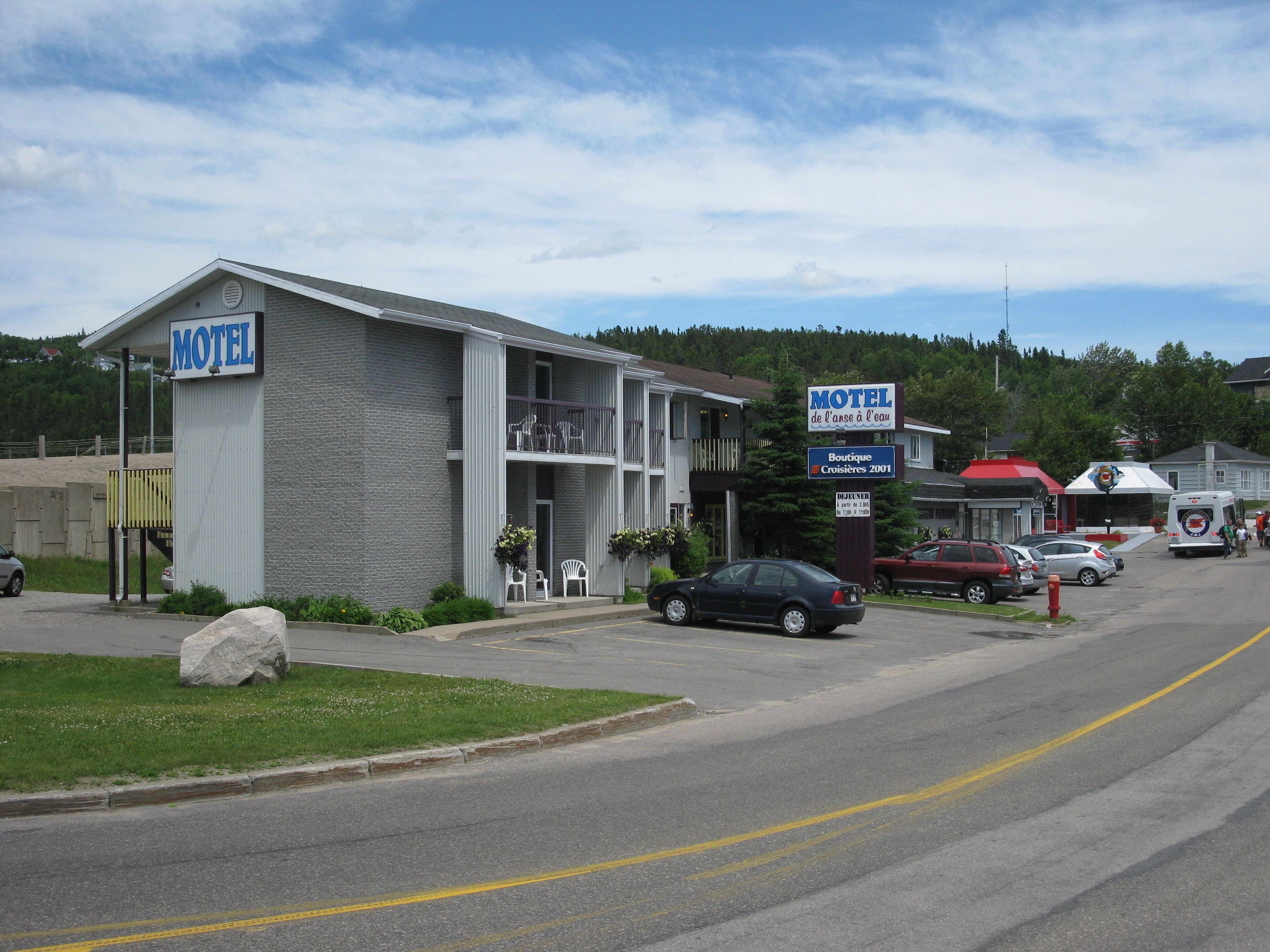 A motel with a signboard, a parking lot, and a road.