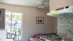 Una cocina con estufa, lavamanos y ventilador de techo.