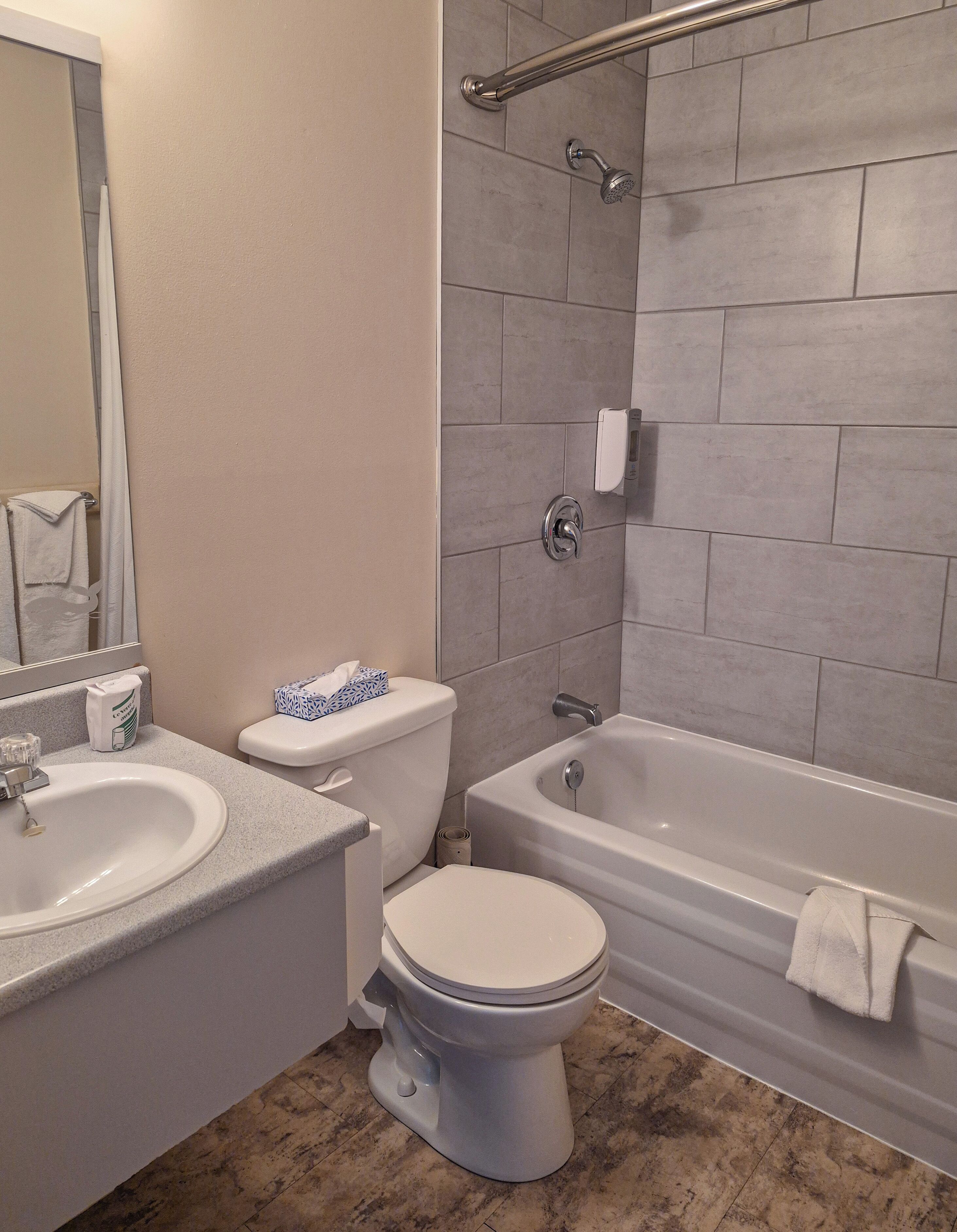 A bathroom with a sink, toilet, bathtub, and a shower area.
