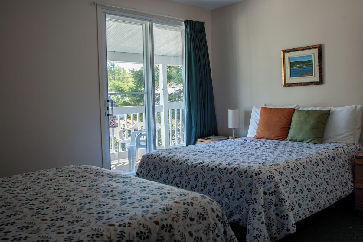 Habitación de hotel con dos camas, un balcón y un cuadro en la pared.