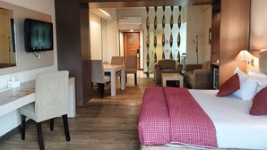 A hotel room with a bed, a desk, a chair, a TV, and a bathroom visible through a door. - Tychi Hotel (Malang)