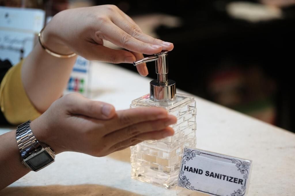 A hand sanitizer dispenser on a counter with a label reading "HAND SANITIZER".