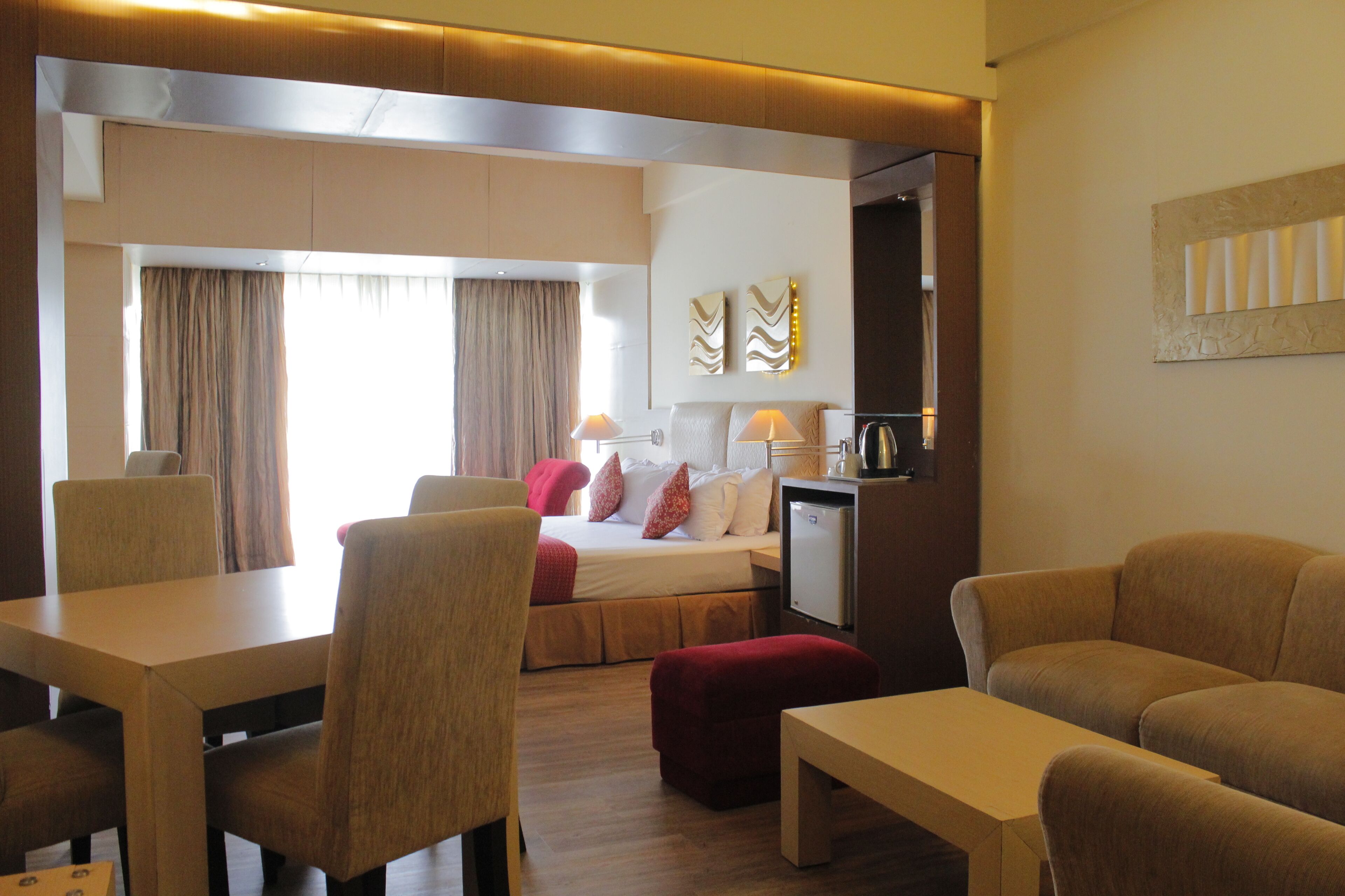 A hotel room with a bed, a desk, a dining table, and a sofa.