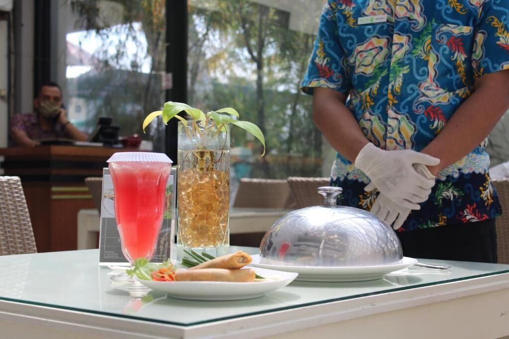 A restaurant table with a drink, a plate of food, and a covered dish.