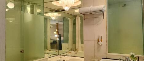 Un baño moderno con un espejo grande, una lámpara de araña, una bañera y un lavamanos.