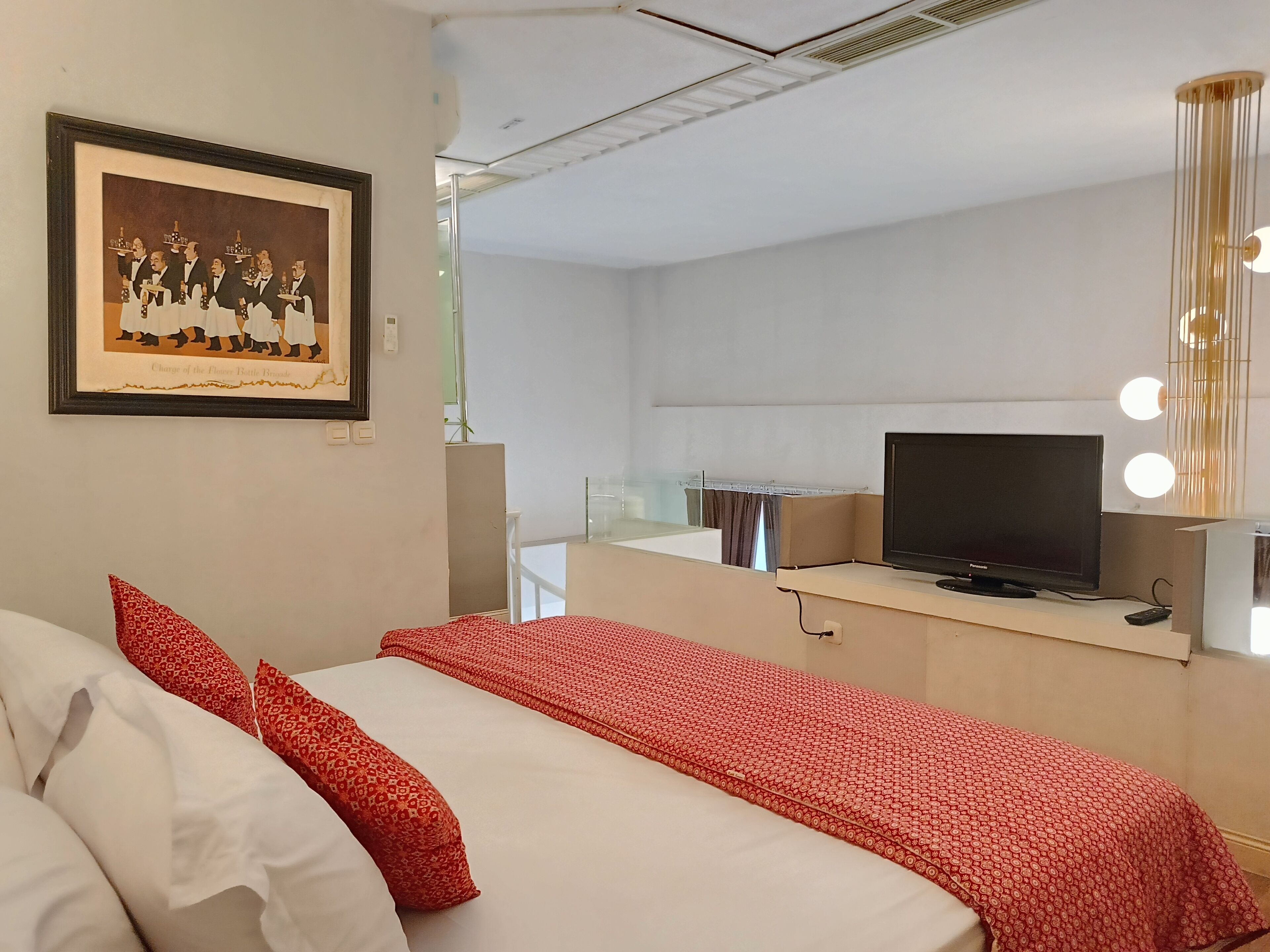 A hotel room with a bed, a television, and a mirror with lights.