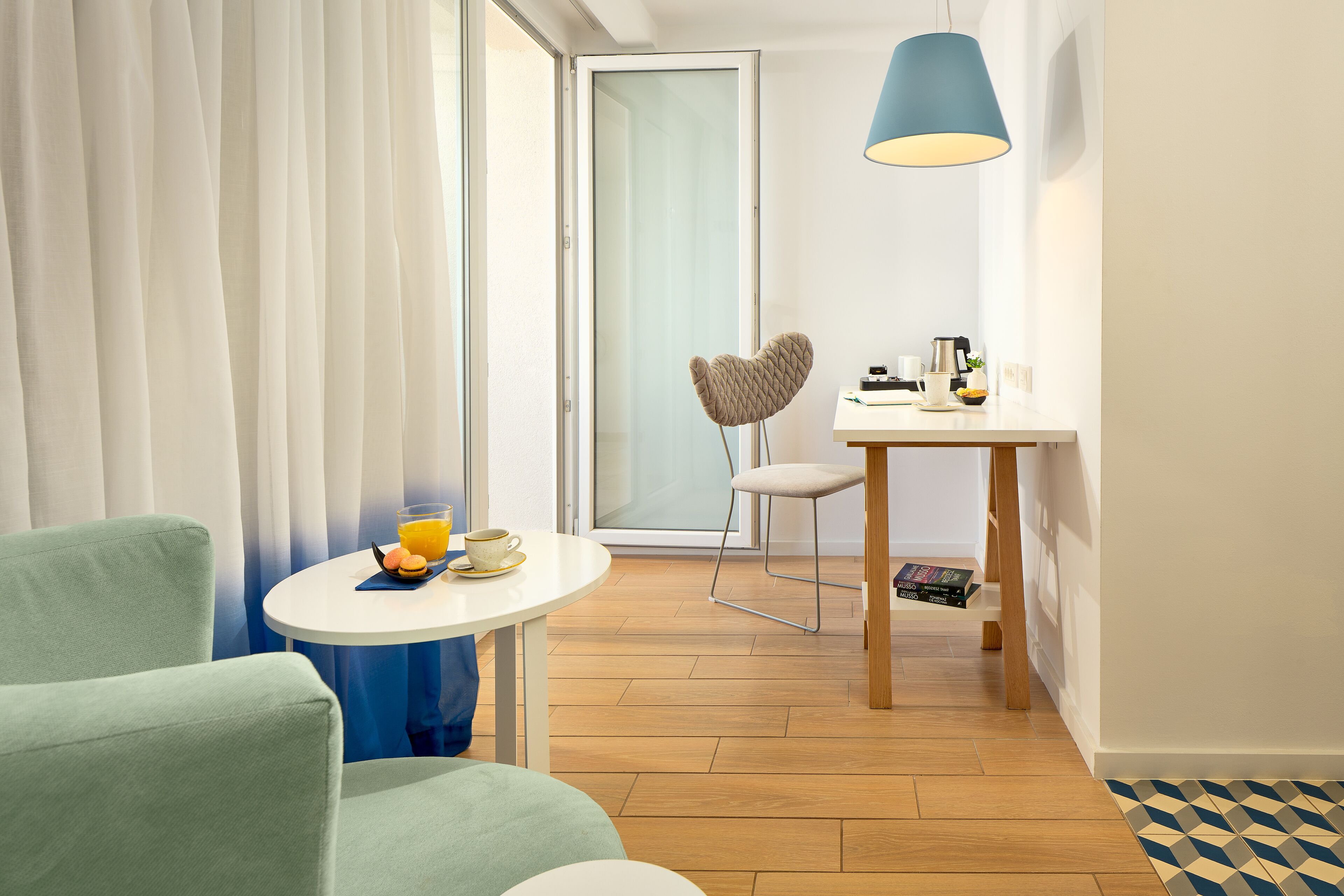 Ein modernes Hotelzimmer mit Essbereich, einem herzförmigen Sessel und einem Tisch mit Lampe.
