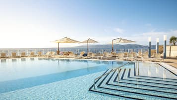 Una piscina al aire libre de temporada, sombrillas