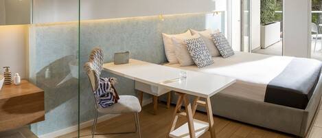 A modern bedroom with a bed, bedside table, chair, and a view of the outdoors.