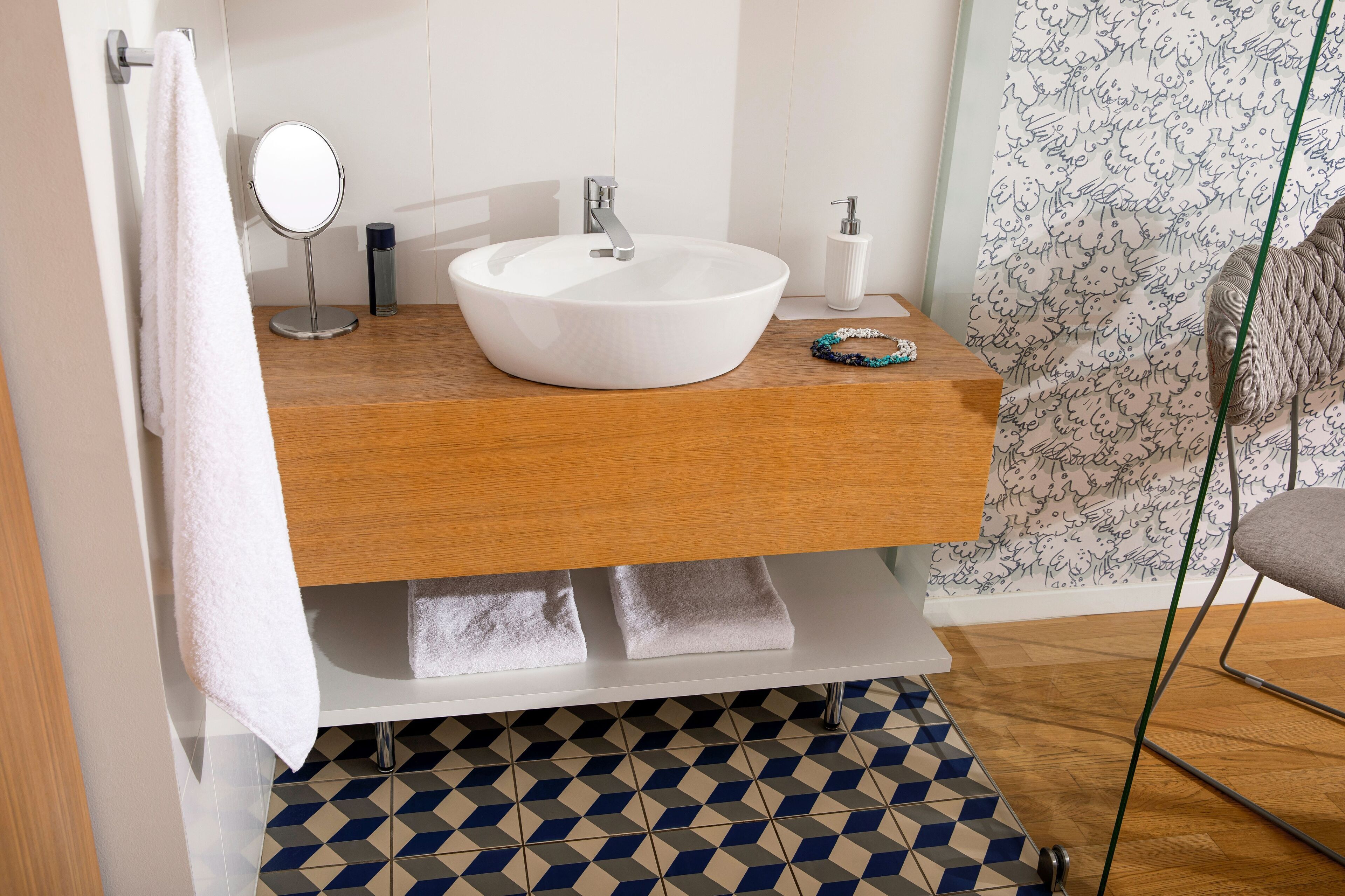 Un baño con un lavabo blanco redondo, un espejo y un perchero para toallas.