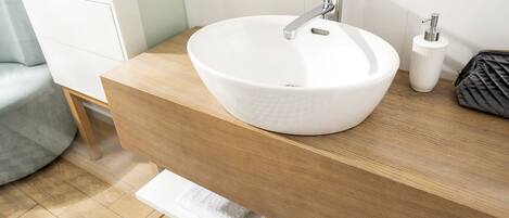 A bathroom with a white vessel sink, wooden countertop, and a towel rack.