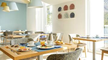 A bright dining area with multiple tables and chairs, a coffee station, and a view of the outdoors.