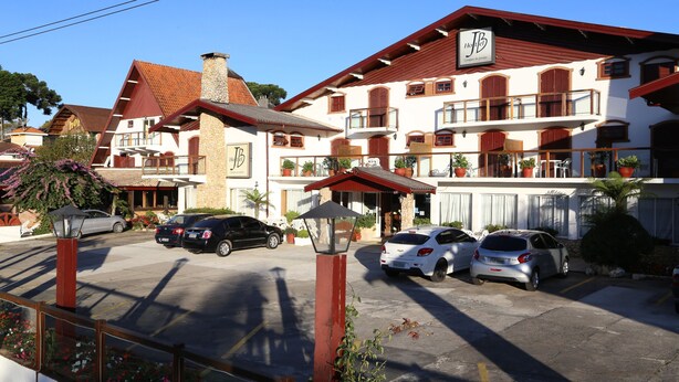 A hotel with multiple balconies, a parking lot, and potted plants. - Hotel JB (Campos do Jordão)