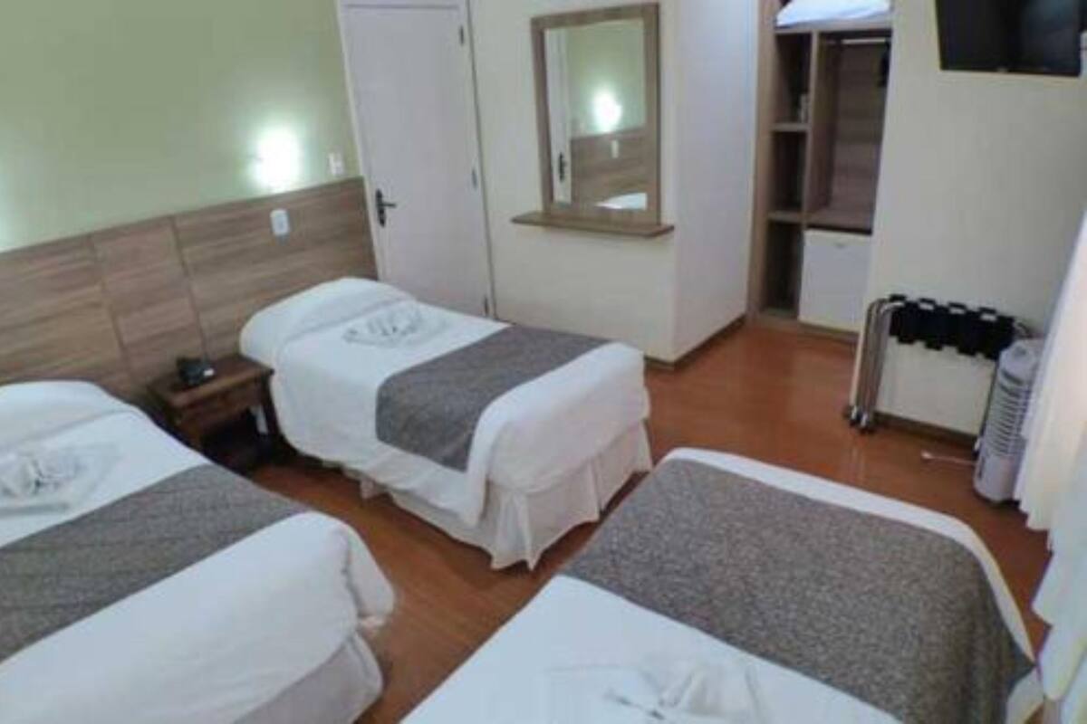 A hotel room with two beds, a wardrobe, a mirror, and a heater.