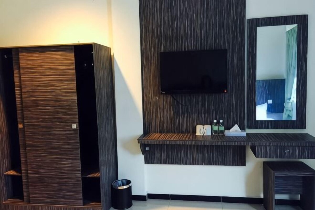 A modern bathroom with a wooden vanity, a mounted TV, and a mirror.