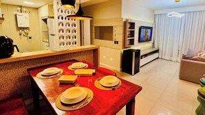 Una sala moderna con televisor, sofá y comedor listo para una comida.