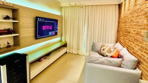 Una sala de estar moderna con un televisor de pantalla plana montado en una pared de madera, un sofá con cojines y una pared decorativa de ladrillo.