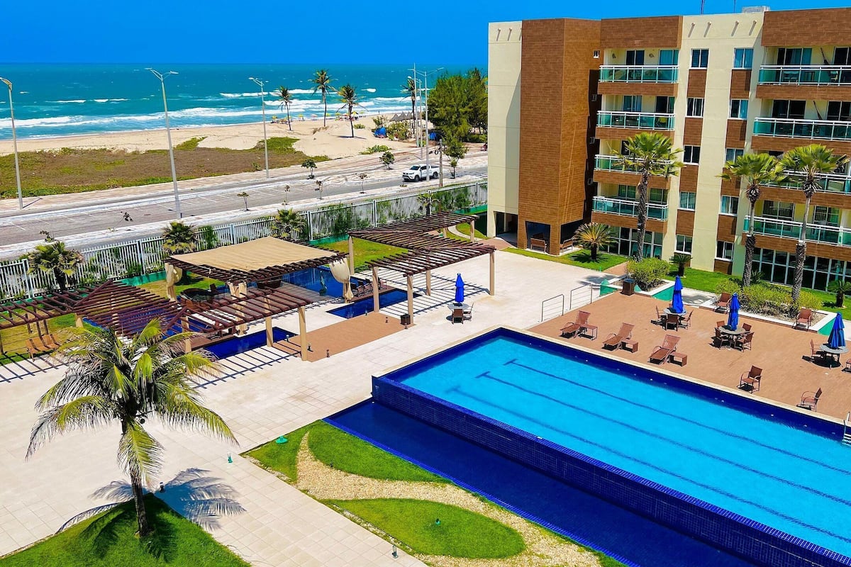 A hotel with a swimming pool, outdoor seating, and a view of the beach.