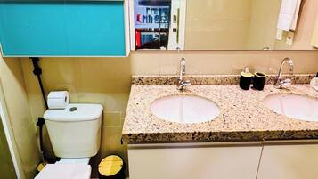 A bathroom with a toilet, two sinks, and a mirror.