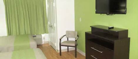 A room with a bed, a chair, a TV, and a dresser.