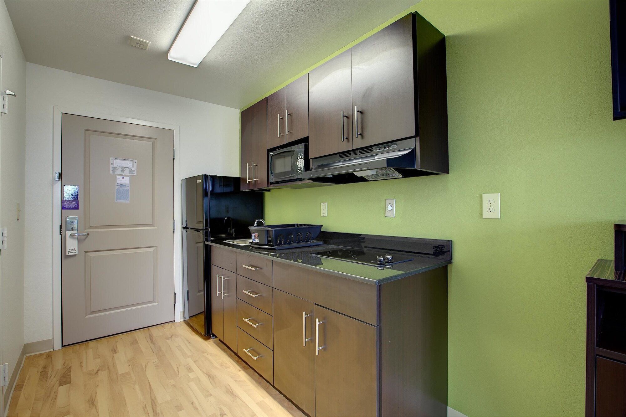 A compact kitchen with a microwave, stove, and wooden cabinets.