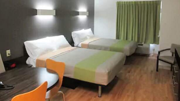 A hotel room with two beds, a small table, and a chair. - Studio 6 Sweetwater, TX (Sweetwater)