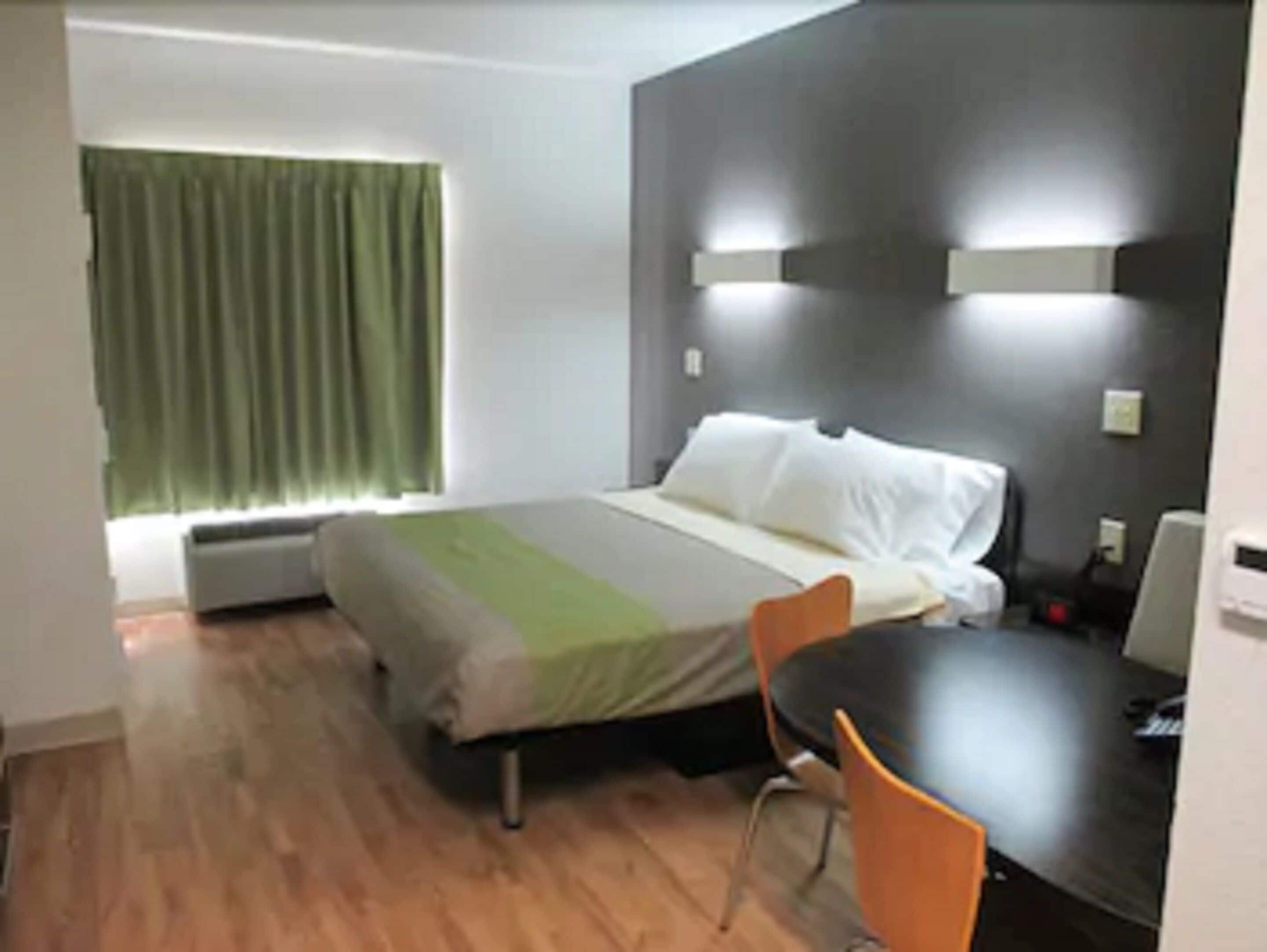 Quarto de hotel com cama, escrivaninha e cadeira.