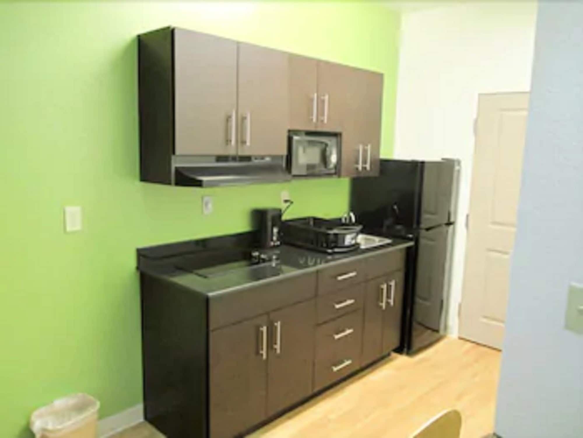 A kitchen with brown cabinets, a microwave, a stove, and a refrigerator.
