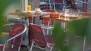 A dining area with tables and chairs, a basket of bread, and a glass of orange juice. - Hotel Le Terminus d'Albi (Albi)