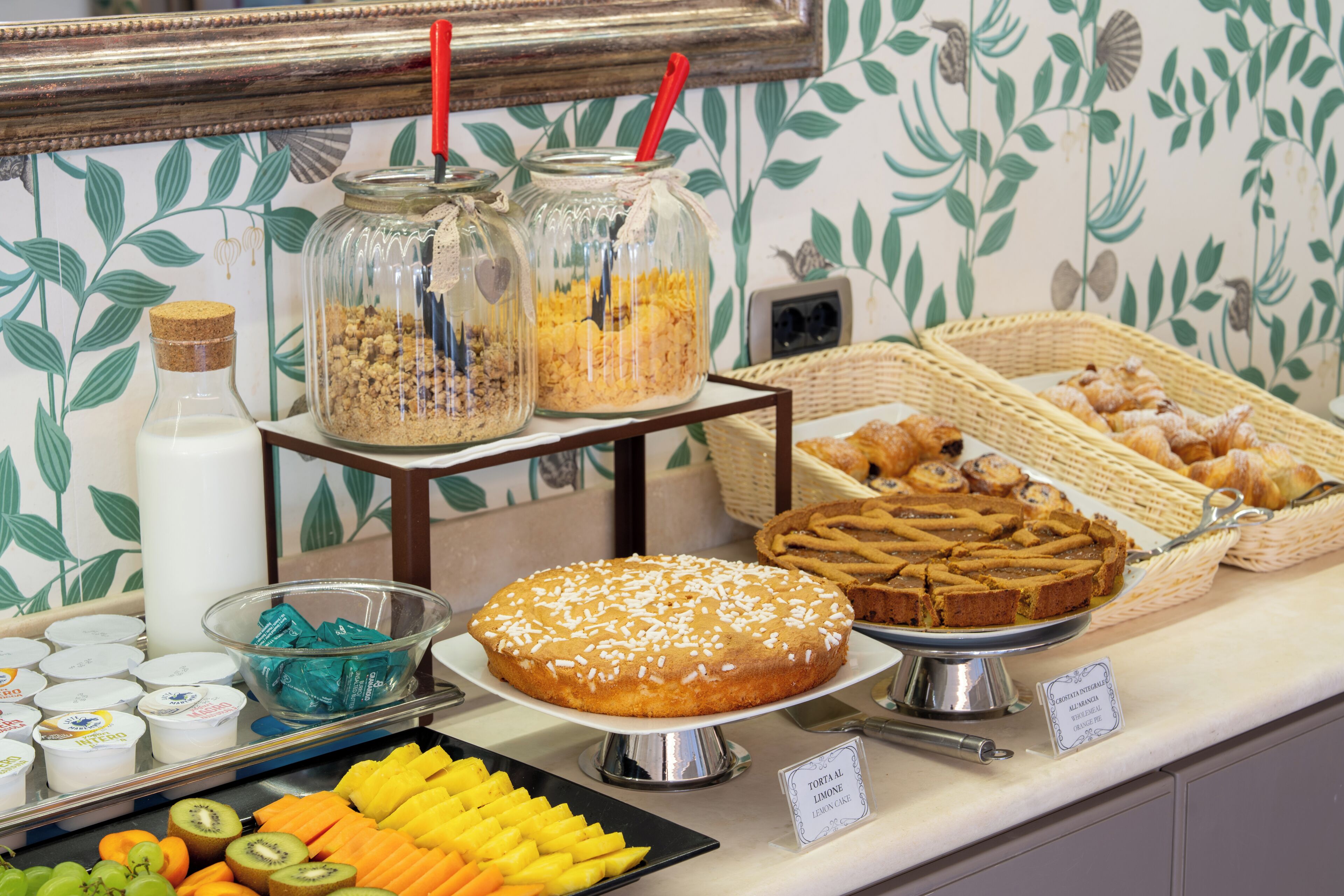 Un buffet proposant une variété de plats, notamment un gâteau recouvert de glaçage blanc, des fruits et des récipients contenant de la nourriture.