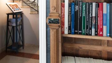 Una estantería de madera llena de libros, una escalera de metal y una pequeña mesa con una revista.
