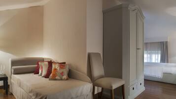 Quarto de hotel com cama, cadeira, mesa de cabeceira e guarda-roupa.