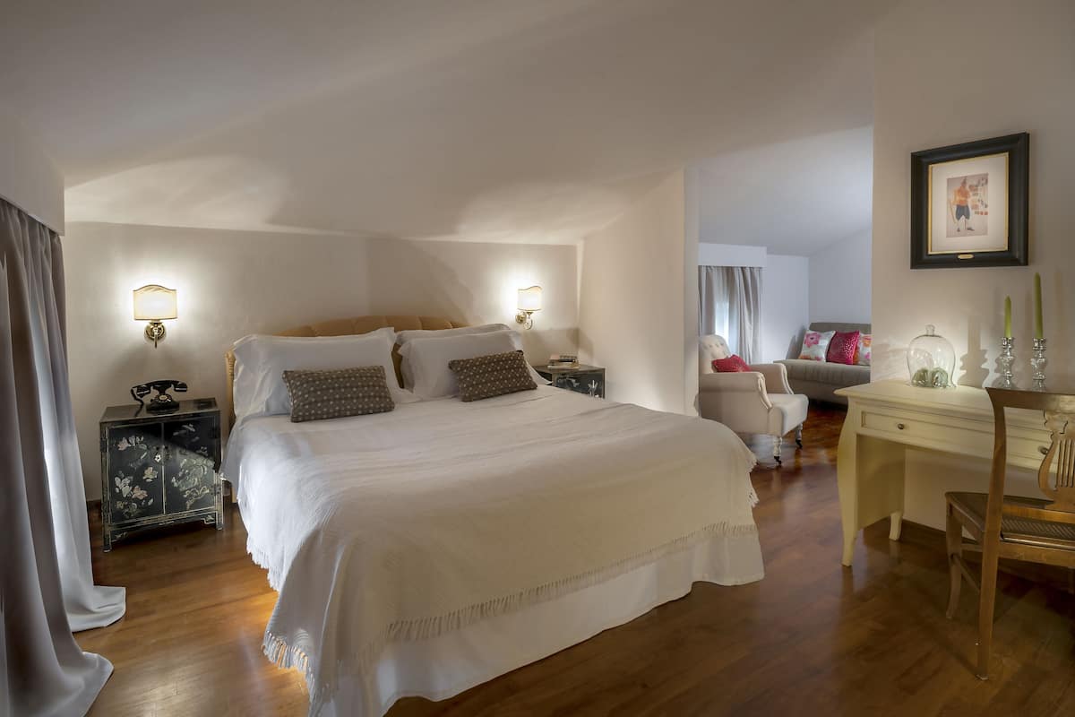 A hotel room with a large bed, two bedside tables, a desk, and a chair.