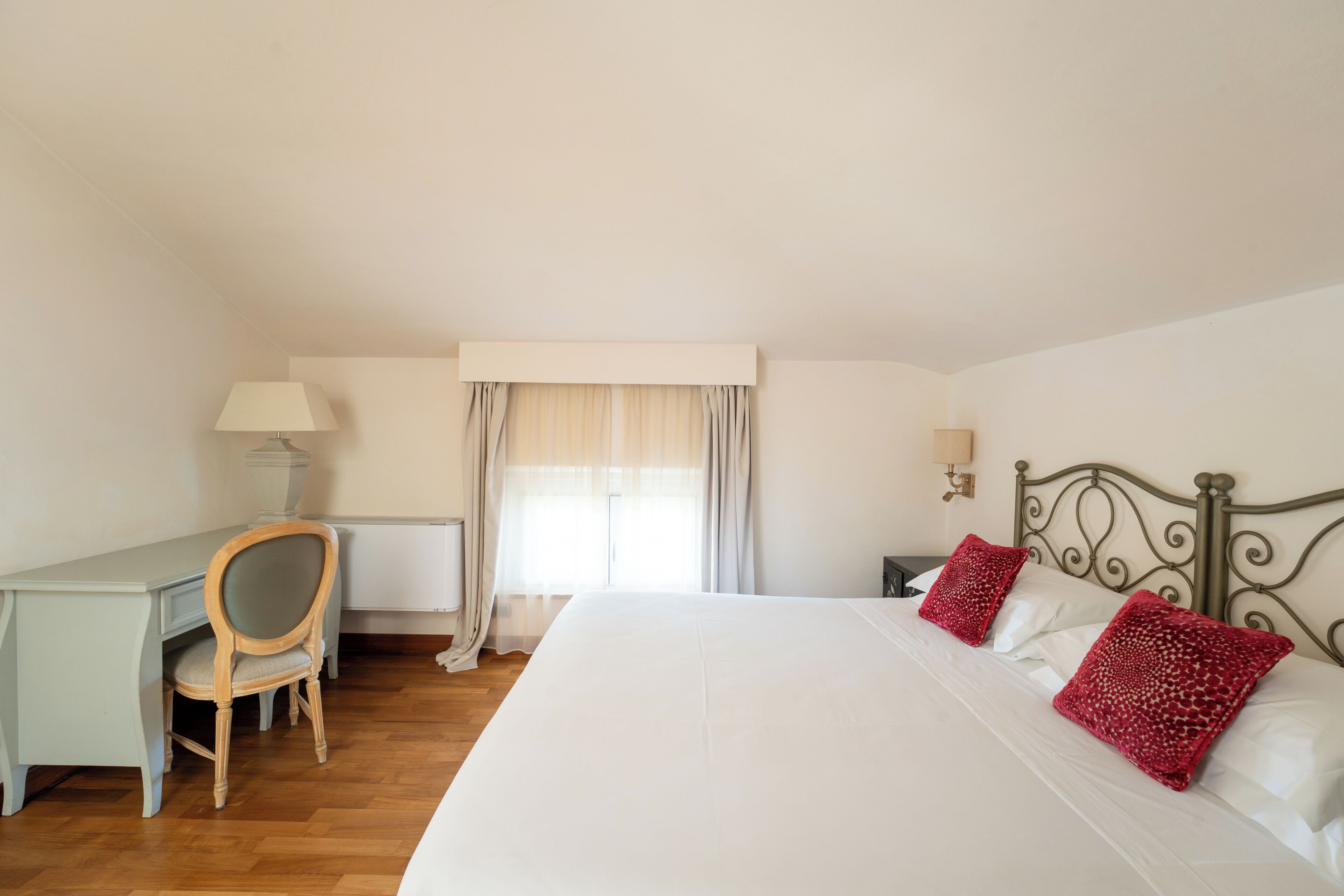Une chambre à coucher avec un lit, un bureau, une chaise et une fenêtre avec des rideaux.