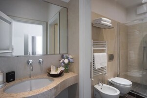 Un bagno moderno con un lavandino capiente, uno specchio, un bidet e una cabina doccia in vetro.