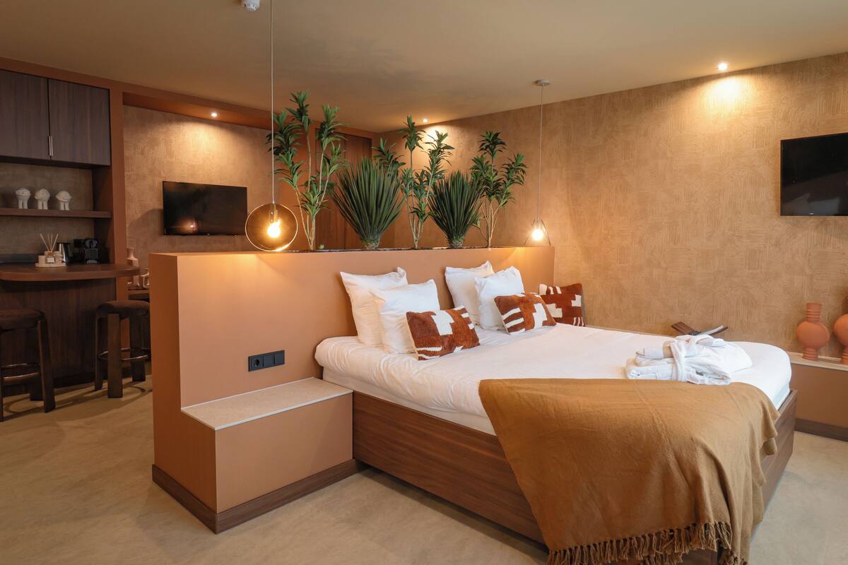 A modern bedroom with a bed, bedside tables, a desk, and a TV.