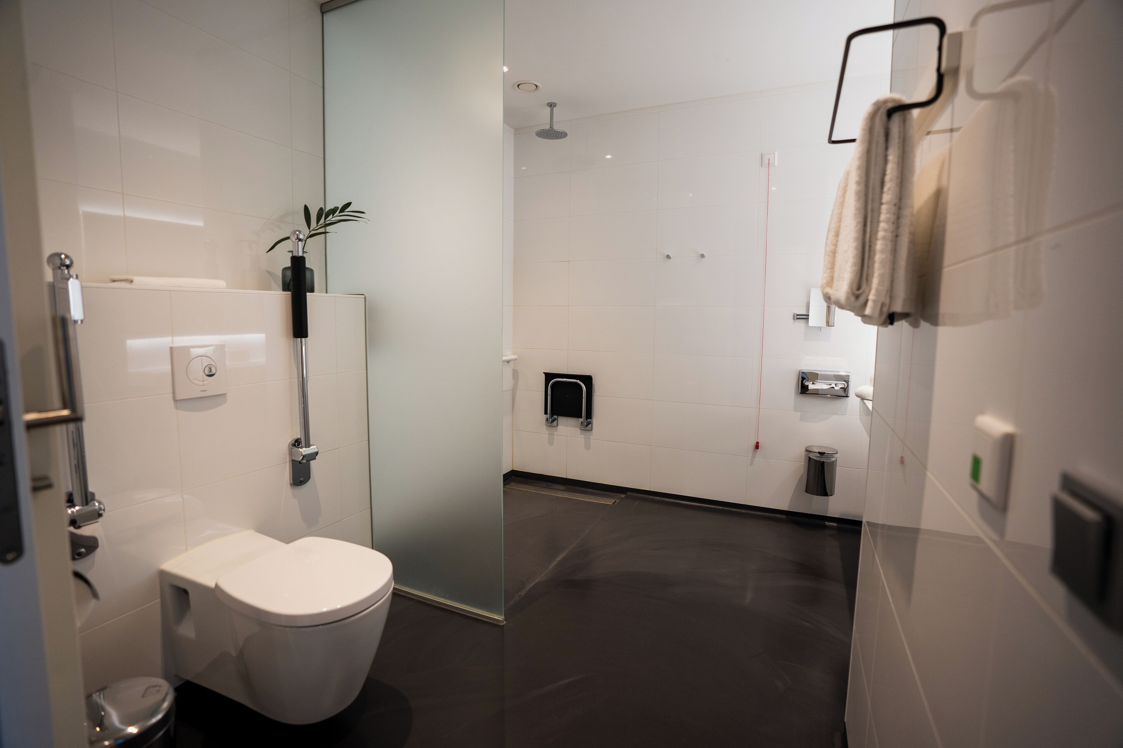 Un baño moderno con inodoro, cabina de ducha de vidrio y un perchero para toallas.