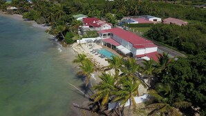 Une propriété située en bord de mer, dotée d’une piscine, de plusieurs bâtiments et de palmiers.