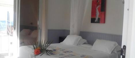 A bedroom with a bed, a door, and a painting on the wall.
