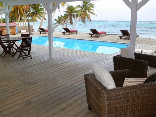 Eine Holzterrasse mit Pool, Liegestühlen und einem Tisch.