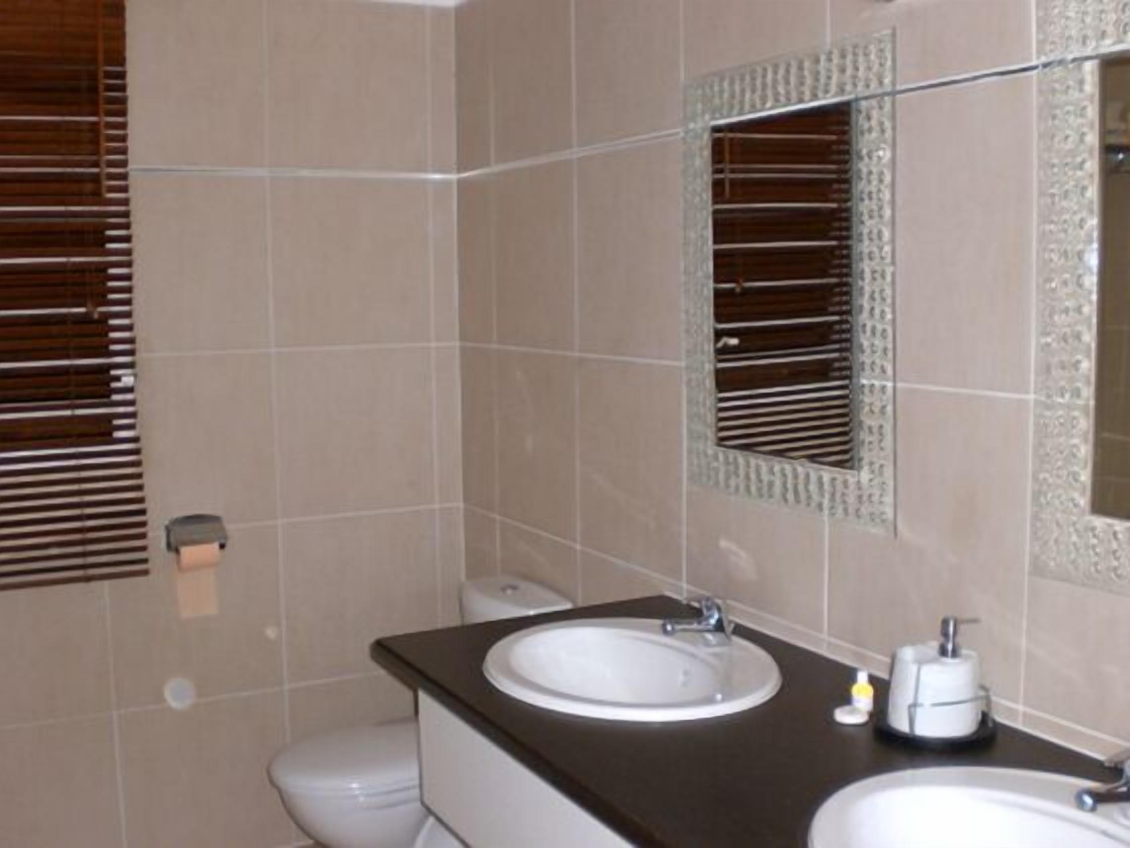 Un baño con dos lavamanos, un inodoro y un espejo.