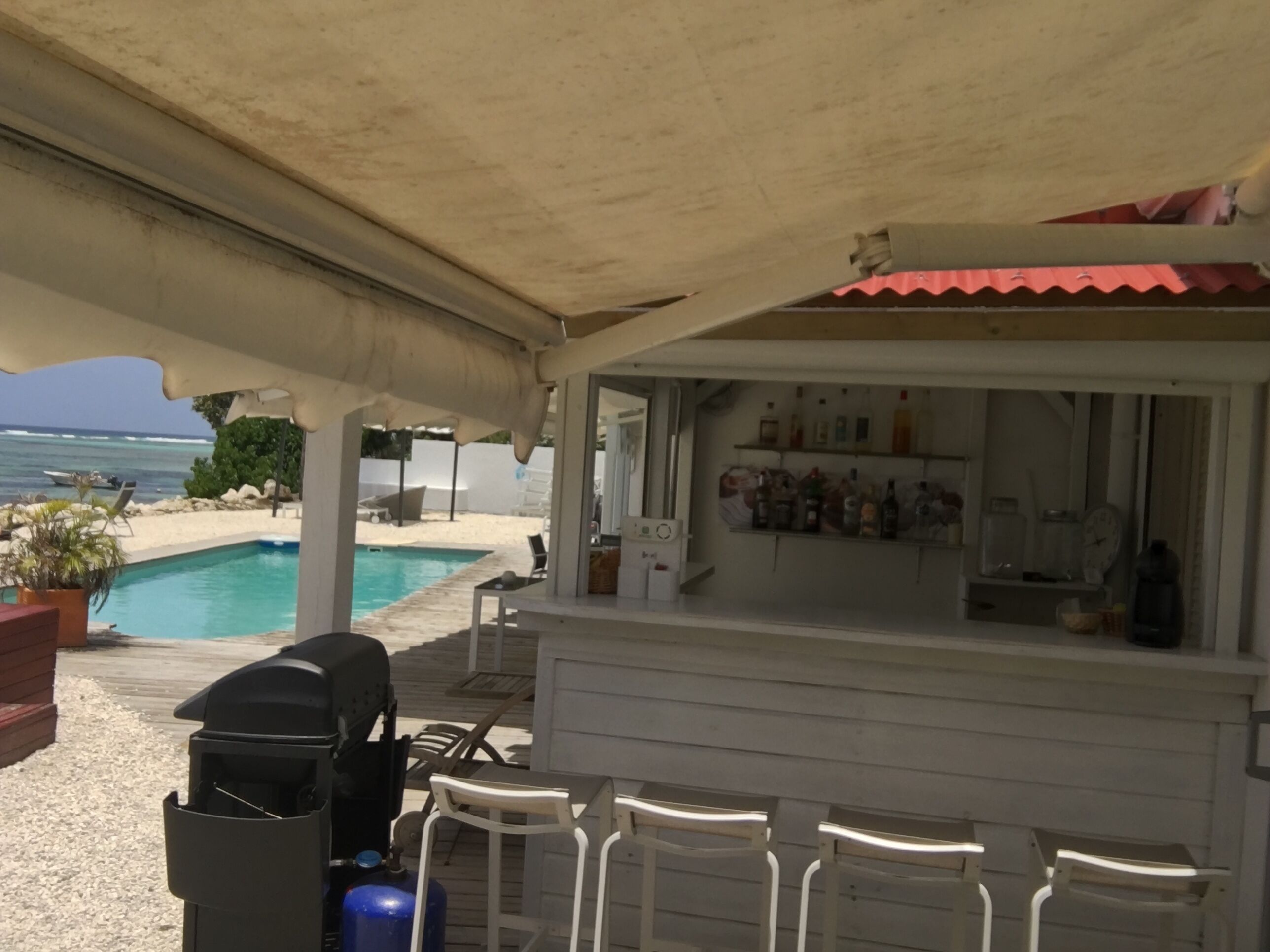 Een poolbar met een grill, barstoelen en uitzicht op de oceaan.