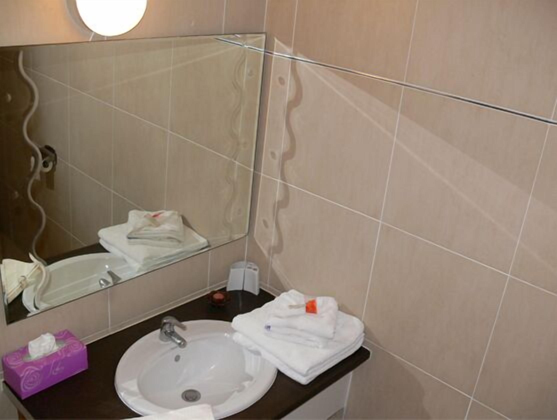Un baño con un lavabo redondo, un espejo y un perchero para toallas.