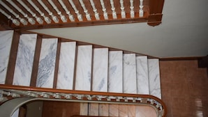 A marble staircase with a wooden handrail and a curved landing.