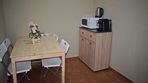 A compact kitchen with a wooden table, white chairs, a microwave, and a cabinet.