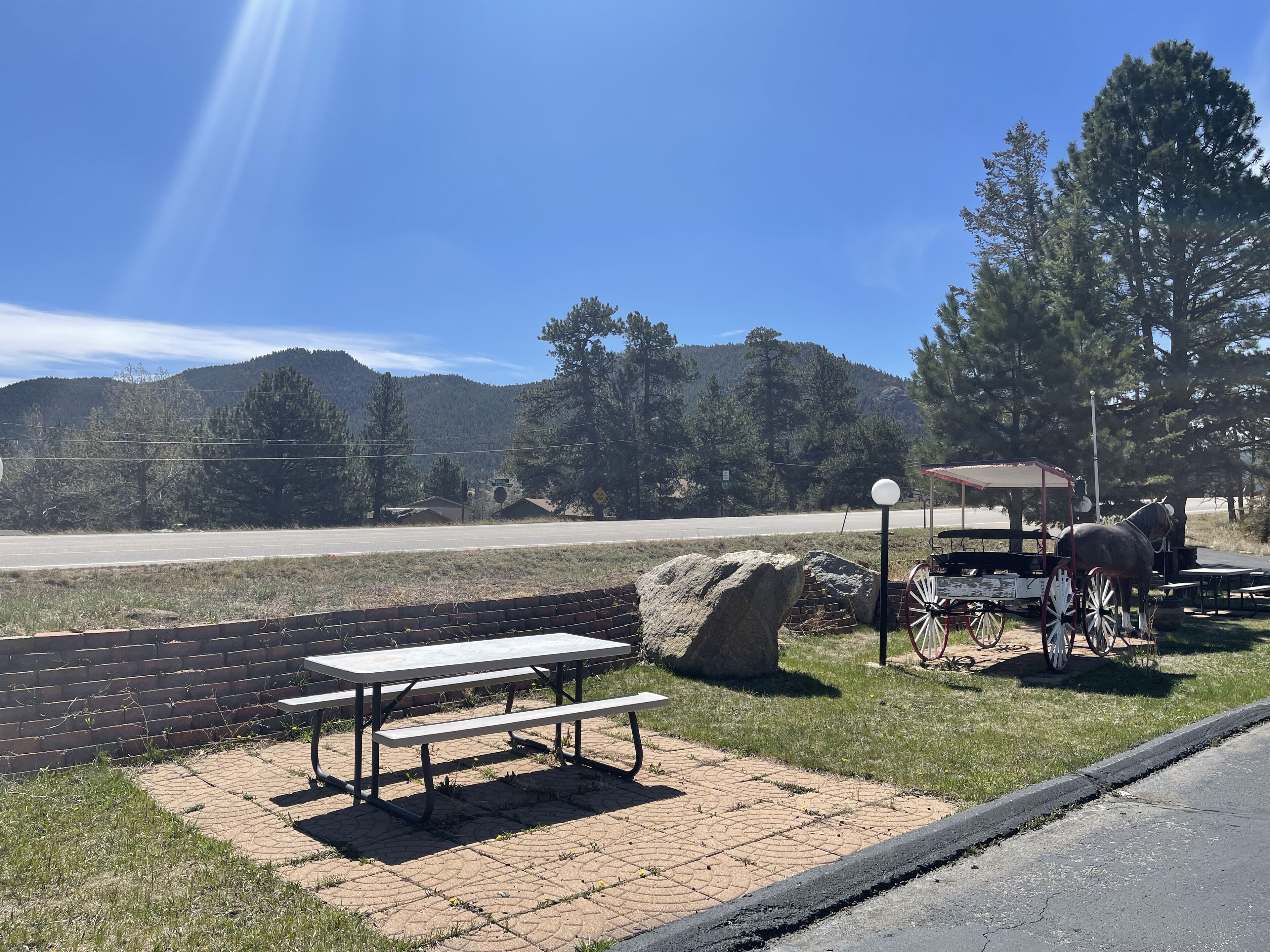 A picnic area with a table and benches, a horse-drawn carriage, and a scenic mountain backdrop.