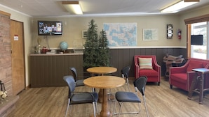 Een hal met een houten receptiebalie, een kerstboom, een kaart aan de muur en een rode bank.