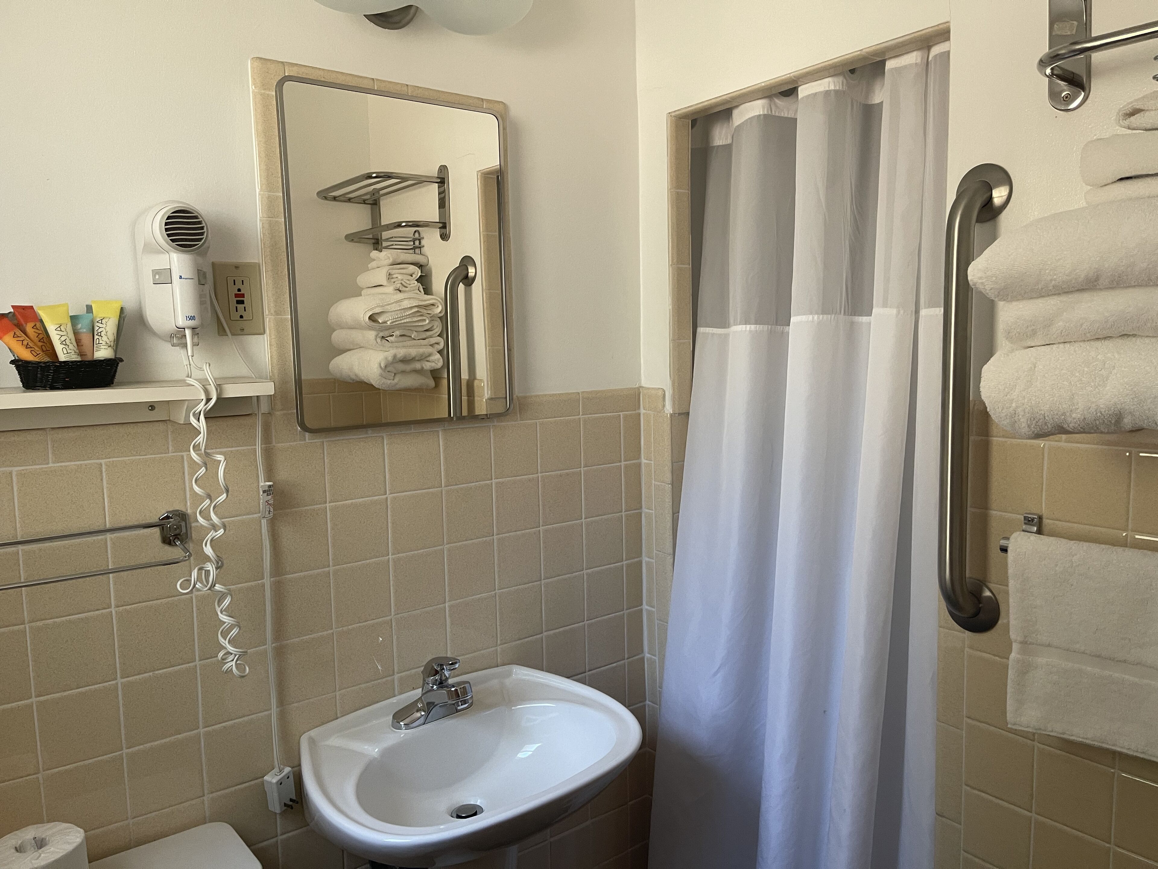 A bathroom with a sink, mirror, towel rack, and shower curtain.